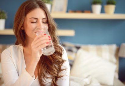 a woman drinking glass on Ways to Up Your Water Intake This Winter