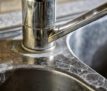 Close-up of a kitchen tap and sink with hard water calcification.